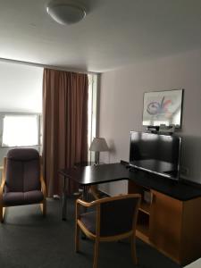a hotel room with a desk and a chair at Business apartment in 3 star hotel Daimler Nah in Sindelfingen +2 photos