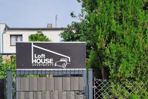 a sign for a lot house in front of a fence at Loft House Noclegi Nysa in Nysa