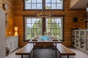 a dining room with a table and benches and windows at Kurjenkenkä by HiYlläs in Kittilä