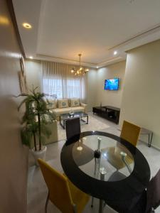 a living room with a table and a couch at appartement pour vacances avec piscine in Bouznika