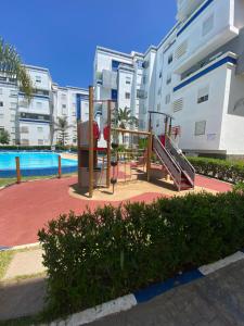 a playground with a slide in front of a building at appartement pour vacances avec piscine in Bouznika