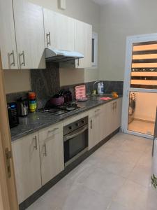 a kitchen with white cabinets and a stove top oven at appartement pour vacances avec piscine in Bouznika
