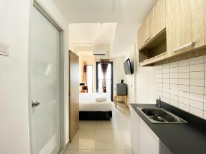 a kitchen with a sink and a bed in a room at Compact and Comfortable Studio Sayana Bekasi Apartment By Travelio in Bekasi