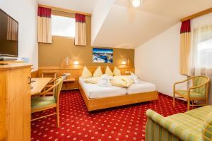 a hotel room with two beds and a desk at Alpen Wohlfühlhotel Dörflwirt in Hainzenberg