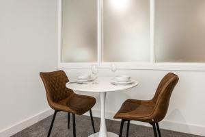 a white table with two chairs and glasses on it at Modern and Spacious Central Rotherham Studio in Rotherham