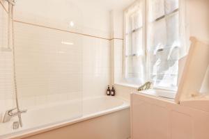 a white bathroom with a tub and a window at Cozy and central apartment in Toulon