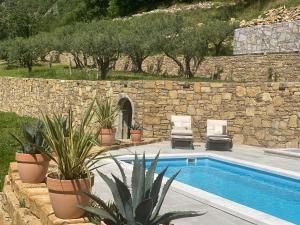 a swimming pool with two chairs and a stone wall at Bubo House in Črni Kal