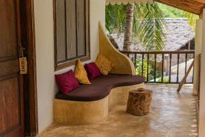 a bench with pillows on a porch with a tree stump at Mr Kahawa in Paje +160 photos