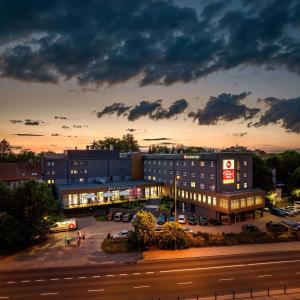 ein Gebäude mit Autos auf einem Parkplatz in der Dämmerung in der Unterkunft Best Western Plus Hotel Olsztyn Old Town in Olsztyn