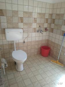 a bathroom with a toilet and a red bucket at Kunsal Yourdum Homestay Ladakh by LexStays in Leh