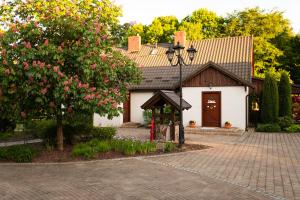 a white house with a tree and a brick driveway at Siedlisko Domkowo in Gierzwałd