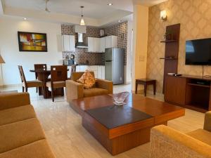 a living room with a couch and a table and a kitchen at Ahuja Residency Noida in Noida