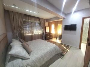 Un dormitorio con una cama blanca y un televisor. en Beach Marina Center, en Tánger