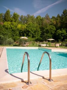 a swimming pool with blue water and two umbrellas at laCelletta Country House in Urbino