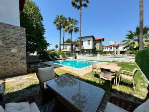a patio with a table and chairs and a pool at Villa Merry - Dalyan Stonehouse with Palmtrees, 50m to River in Ortaca