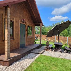a wooden cabin with a porch and an umbrella at Domek dla dwojga in Pelnik +23 photos