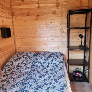 a bed in a room with a wooden wall at Domek dla dwojga in Pelnik