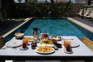 a table with food and drinks next to a swimming pool at Marrakesh Alaçatı in Ildır
