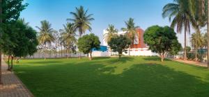 a green park with palm trees and a building at Goldfinch Retreat Bangalore in Devanahalli-Bangalore