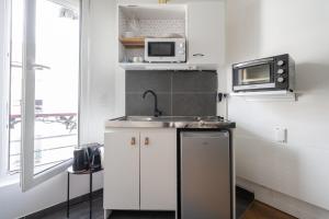 Una pequeña cocina con fregadero y microondas. en Studio Ginoux - Welkeys, en Montrouge 4 fotos más