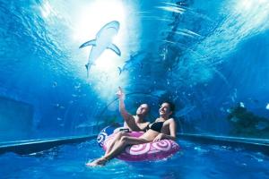 two girls sitting on an inflatable whale in the water at Domki Przy Tężni in Karwia