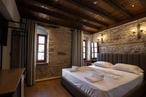 een slaapkamer met een bed en een bakstenen muur bij Furra Hotel in Gjirokastër