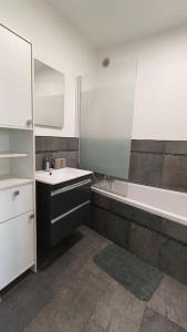 a bathroom with a sink and a tub and a mirror at Appartement lumineux in Argenteuil