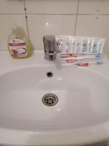a white sink with toothbrushes and toothpaste on it at Двухкомнатная 19-7 in Atyraū