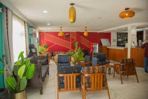 a restaurant with chairs and tables and a red wall at Hôtel La Rose Blanche Abidjan in Abidjan