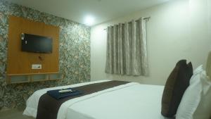 a hotel room with a bed and a flat screen tv at Hotel Mahakal Avantika Palace in Ujjain