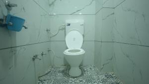 a bathroom with a toilet in a white tiled wall at Hotel Mahakal Avantika Palace in Ujjain