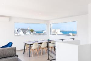 a dining room with white walls and a table and chairs at Villa ELISA Piscine Intérieure partagée chauffée à 29 degrés à 100m de la plage in Sibiril