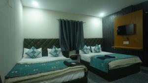 a hotel room with two beds and a flat screen tv at Hotel Mahakal Avantika Palace in Ujjain