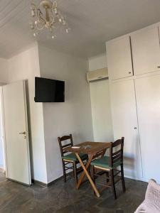 a dining room with a table and chairs and a tv at Studio Villa Emeli, close to beaches and downtown in Porto Heli