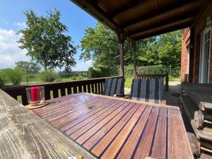 a wooden table and chairs on a deck at A12 Das rote Haus am Haff Roggow Ostseebad Rerik in Roggow +51 photos