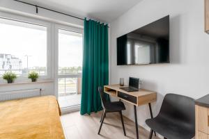 een kamer met een bureau, een computer en een raam bij Chill Apartments Pileckiego in Warschau