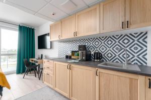 een keuken met houten kasten, een wastafel en een tafel bij Chill Apartments Pileckiego in Warschau +7 foto's