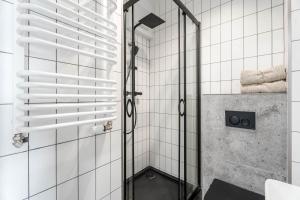 een douche met een glazen deur in een badkamer bij Chill Apartments Pileckiego in Warschau