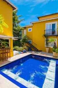 a villa with a swimming pool in front of a house at La Chimère Buzios Essence in Búzios