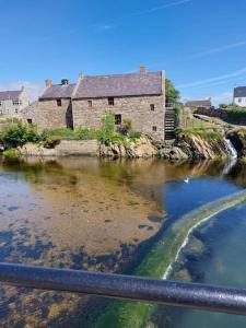 an old building sitting on the side of a river at The Beach House Annalong Cosy beachview cottage in Annalong