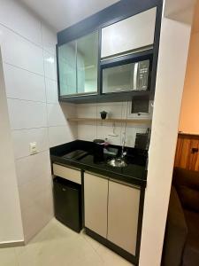 a small kitchen with a sink and a mirror at Roda Gigante, garagem e piscina in Balneário Camboriú