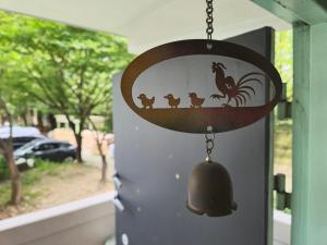 a bell hanging on a door with a chicken and rooster at MIN Stay - Woman Only Homestay in Seoul