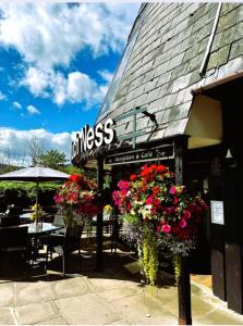 a restaurant with flowers in front of a building at Loch Ness Drumnadrochit Hotel in Drumnadrochit
