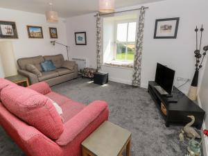 a living room with a red couch and a tv at Grassholm View in Haverfordwest