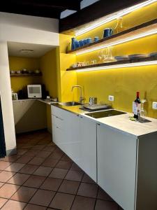 a kitchen with white cabinets and a yellow wall at PortAllegra Charme&Relax in Bergamo +6 photos