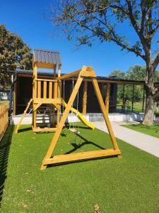 a wooden swing set with a chair on the grass at Chillhouse Császárszállás in Nyíregyháza