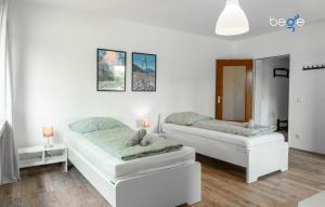 2 Betten in einem Zimmer mit weißen Wänden und Holzböden in der Unterkunft BEGE APARTMENTS Corporate Lodge in Gelsenkirchen