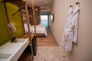 a bathroom with a sink and a bedroom with a bed at JANGA HOTEL BOUTIQUE in Maragogi