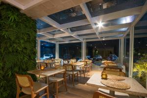 a restaurant with tables and chairs and a wall of windows at JANGA HOTEL BOUTIQUE in Maragogi