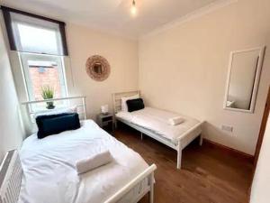 a bedroom with two beds and a mirror at Enjoy A Spacious 3 Br Home in Gateshead +2 photos